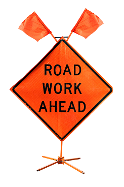 Orange diamond-shaped road sign with "ROAD WORK AHEAD" text. Two small orange flags on top. Indicates construction, warning drivers.