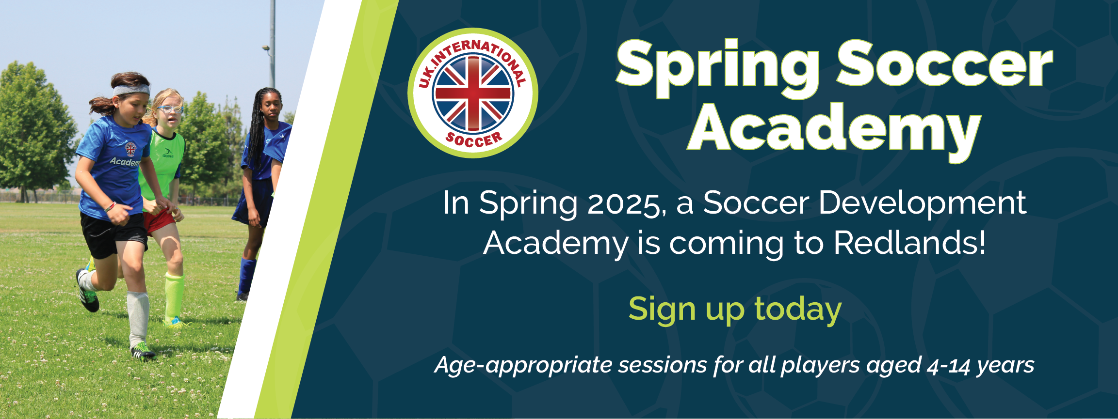 Children playing soccer on a field under a clear sky beside a banner. The banner announces 