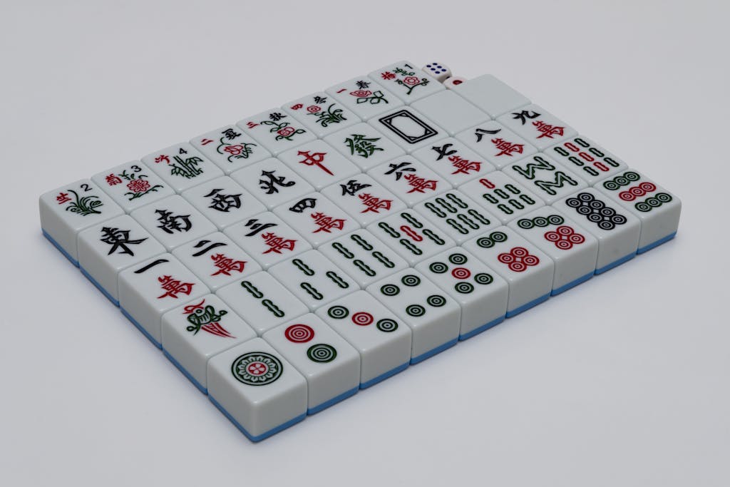 A set of mahjong tiles neatly arranged on a white background, ideal for gaming enthusiasts.