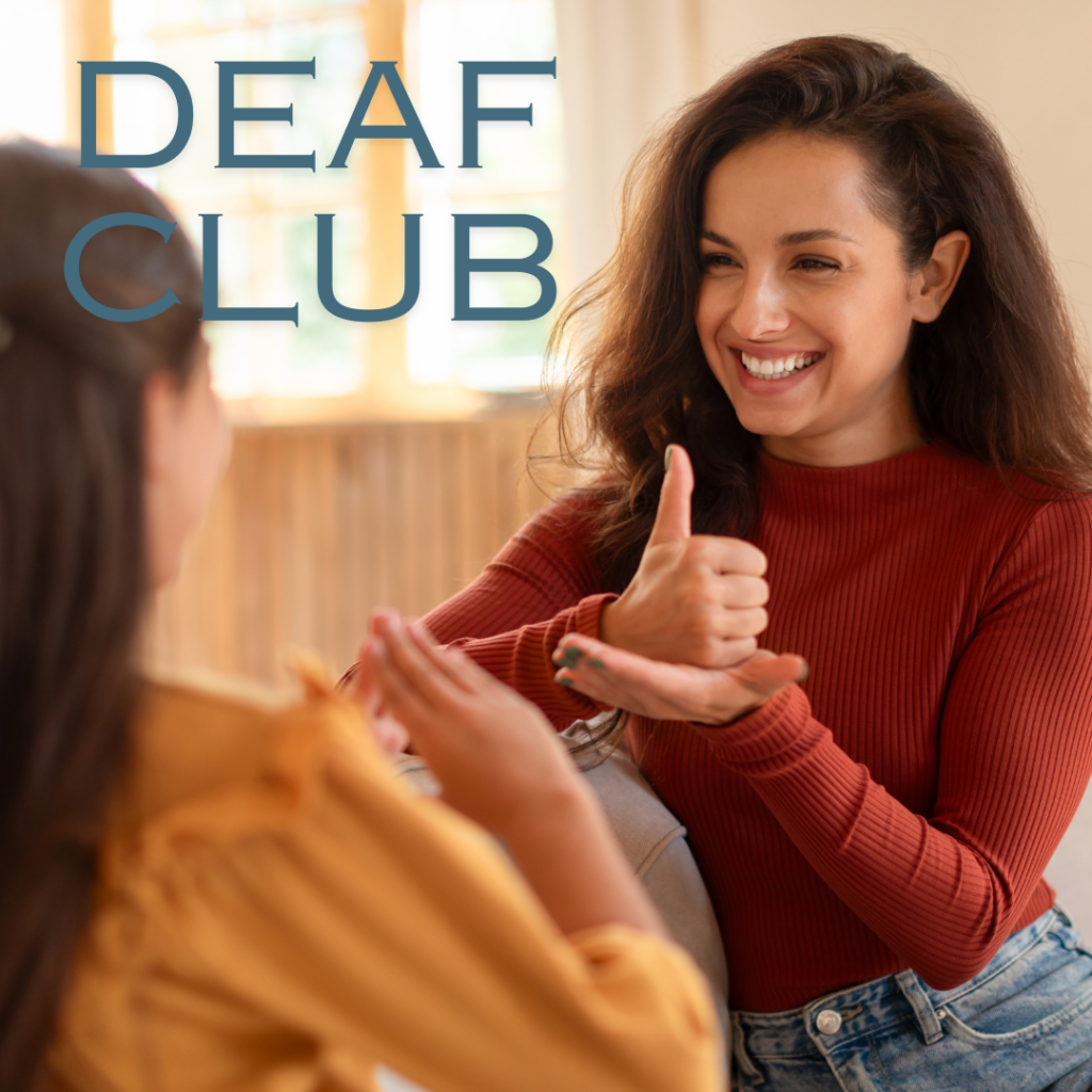 Two women use sign language and smile at each other indoors. The words “DEAF CLUB” are written in large letters in the upper left corner.